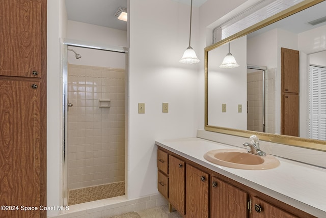 bathroom with tiled shower and vanity