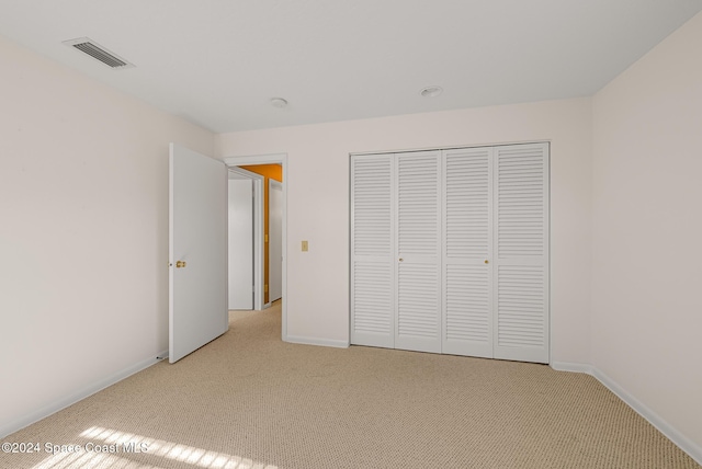 unfurnished bedroom featuring light colored carpet and a closet