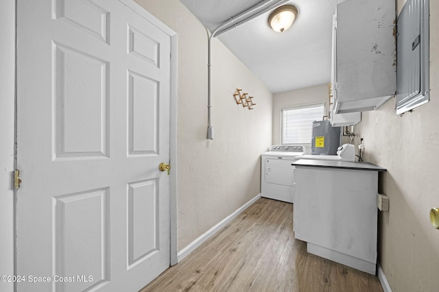 clothes washing area with electric water heater, separate washer and dryer, and light hardwood / wood-style flooring