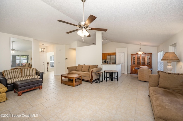 living room featuring a textured ceiling, ceiling fan, light tile patterned floors, and lofted ceiling