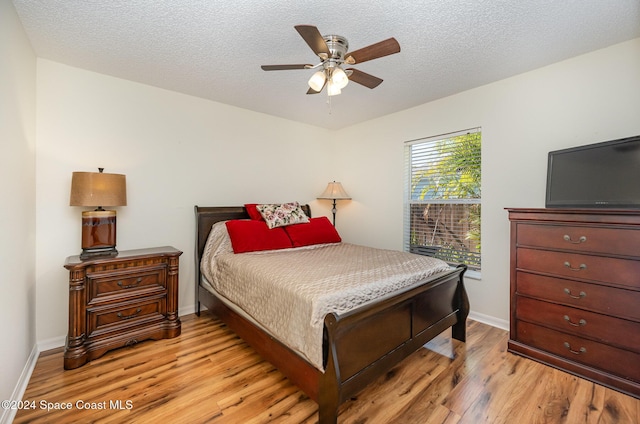 bedroom with ceiling fan, a textured ceiling, and light hardwood / wood-style flooring