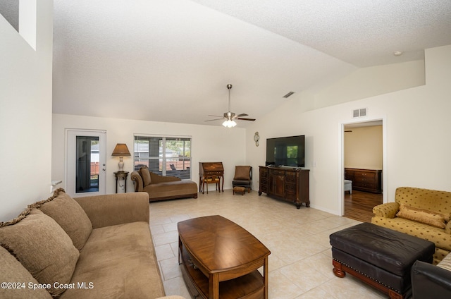 tiled living room featuring a textured ceiling, ceiling fan, and vaulted ceiling