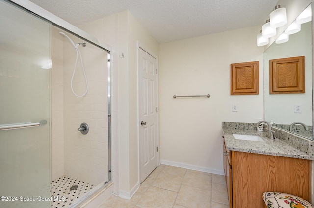 bathroom with tile patterned floors, vanity, a textured ceiling, and walk in shower