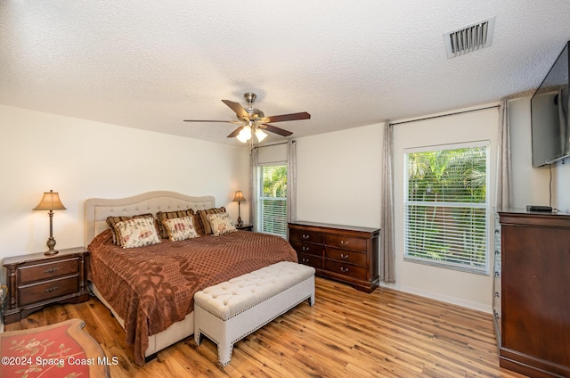 bedroom featuring ceiling fan, a textured ceiling, and light hardwood / wood-style flooring