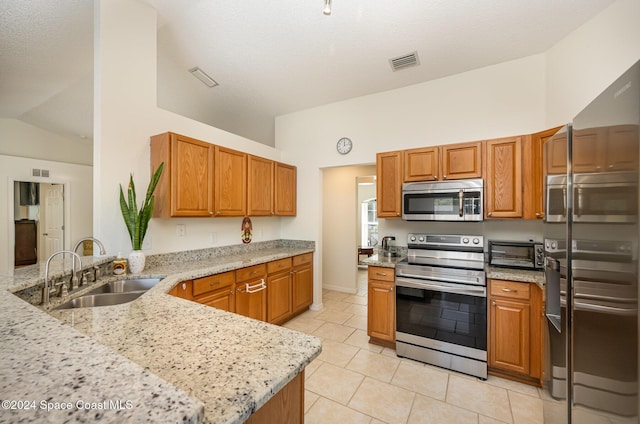 kitchen featuring sink, light stone countertops, light tile patterned flooring, kitchen peninsula, and stainless steel appliances