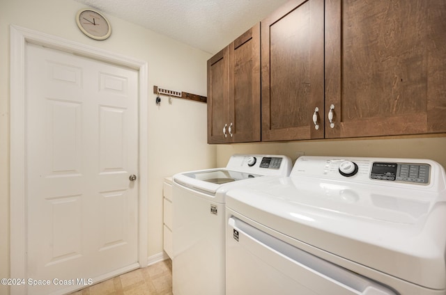 washroom with cabinets, washer and dryer, and a textured ceiling