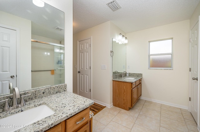 bathroom featuring tile patterned flooring, vanity, a textured ceiling, and walk in shower