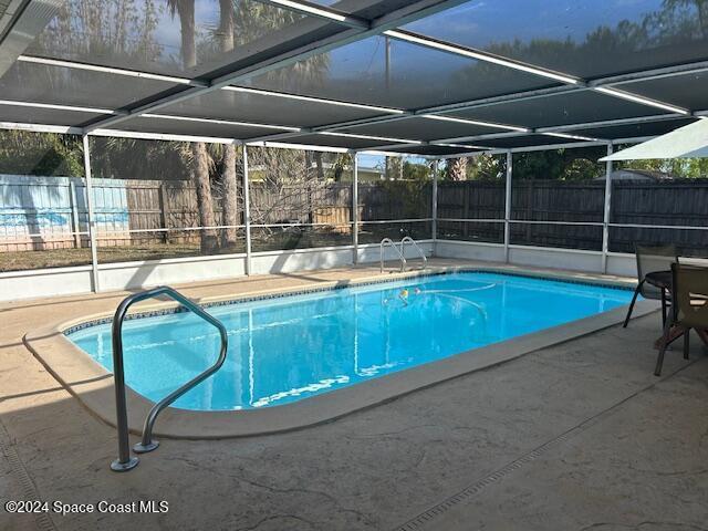 view of swimming pool featuring a lanai and a patio area