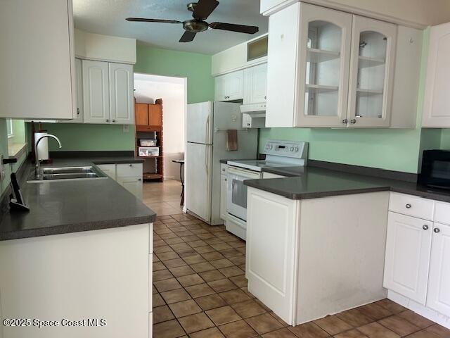 kitchen with white appliances, dark tile patterned flooring, sink, ceiling fan, and white cabinetry