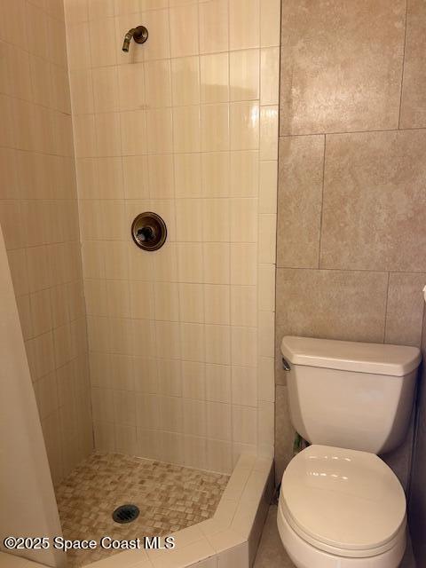 bathroom with a tile shower and toilet