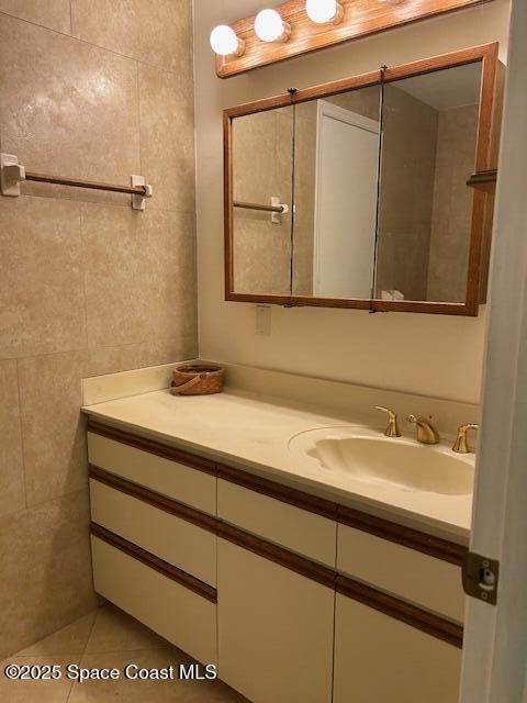 bathroom featuring tile patterned flooring, vanity, and tile walls