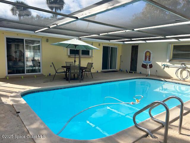 pool featuring glass enclosure and a patio area