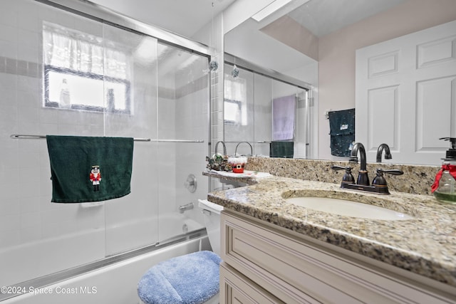 full bathroom with vanity, bath / shower combo with glass door, and toilet