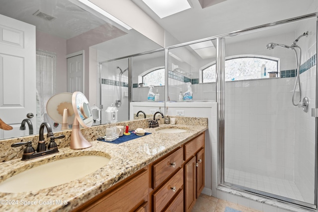 bathroom featuring tile patterned floors, a skylight, a shower with door, and vanity