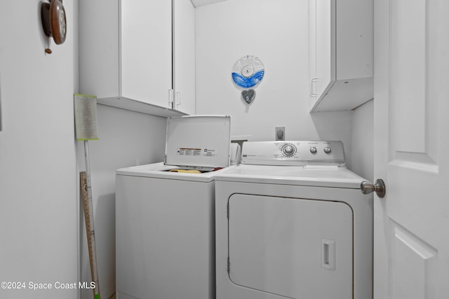 clothes washing area featuring cabinets and washing machine and clothes dryer