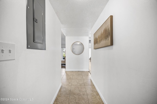 hallway featuring light tile patterned flooring, a textured ceiling, and electric panel