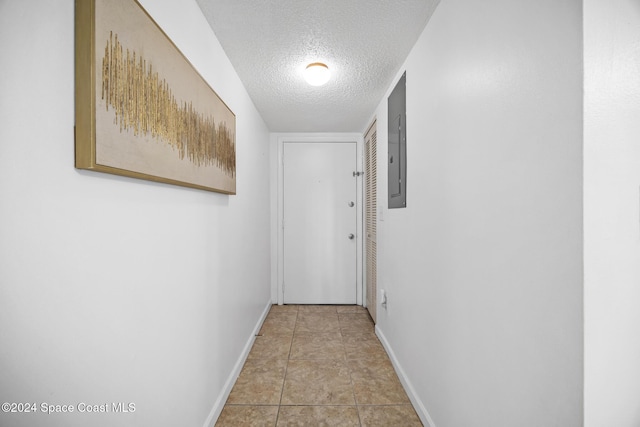 hallway with light tile patterned floors, a textured ceiling, and electric panel