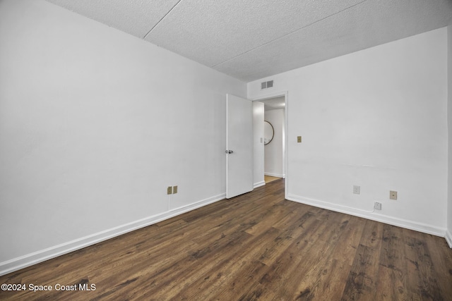 spare room featuring dark hardwood / wood-style flooring and a textured ceiling