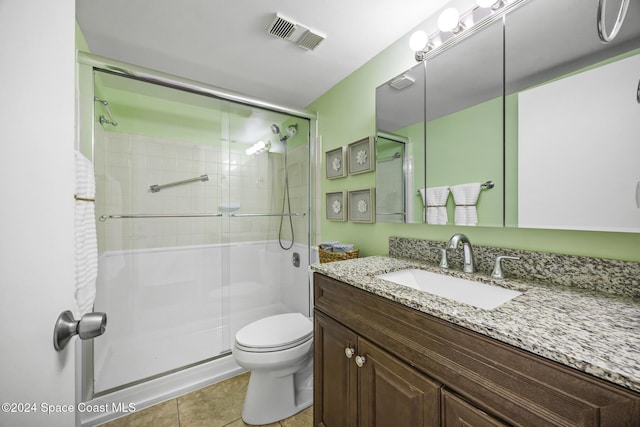 bathroom featuring tile patterned flooring, vanity, a shower with shower door, and toilet