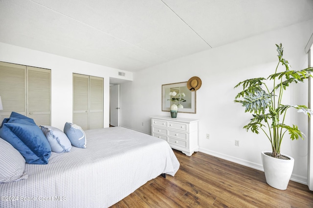 bedroom with dark hardwood / wood-style flooring and multiple closets