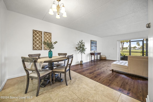 dining room featuring wood-type flooring, a textured ceiling, and an inviting chandelier