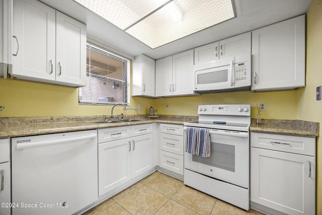 kitchen with white cabinets, light tile patterned floors, white appliances, and sink