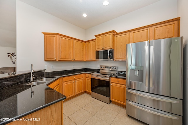 kitchen with kitchen peninsula, appliances with stainless steel finishes, dark stone countertops, and sink