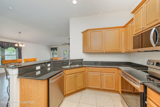 kitchen with kitchen peninsula, appliances with stainless steel finishes, ceiling fan with notable chandelier, sink, and decorative light fixtures