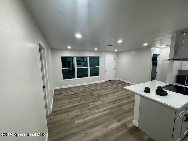 kitchen featuring dark hardwood / wood-style floors, gray cabinets, and wall chimney range hood