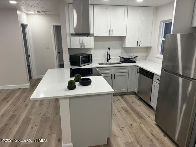 kitchen with sink, a kitchen island, stainless steel appliances, and light hardwood / wood-style floors