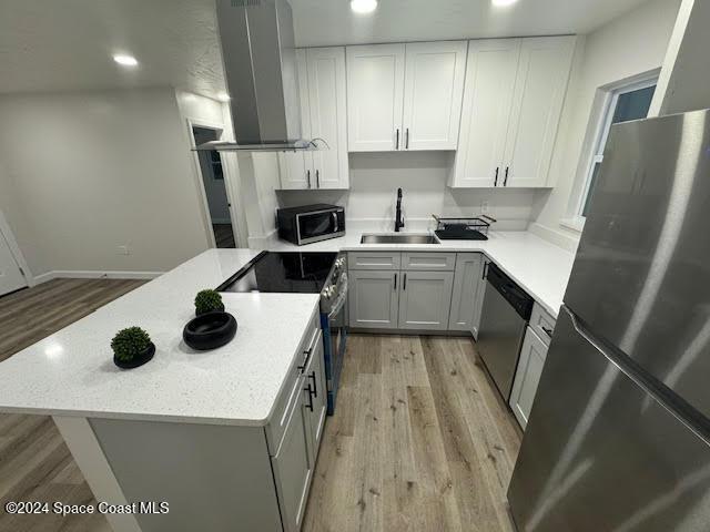 kitchen featuring white cabinetry, sink, wall chimney exhaust hood, stainless steel appliances, and light hardwood / wood-style floors