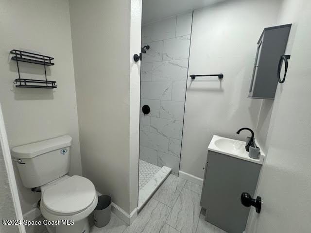 bathroom with tiled shower, vanity, and toilet