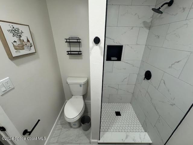 bathroom with a tile shower and toilet