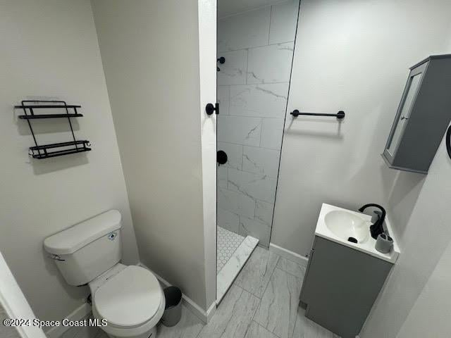 bathroom featuring vanity, toilet, and a tile shower