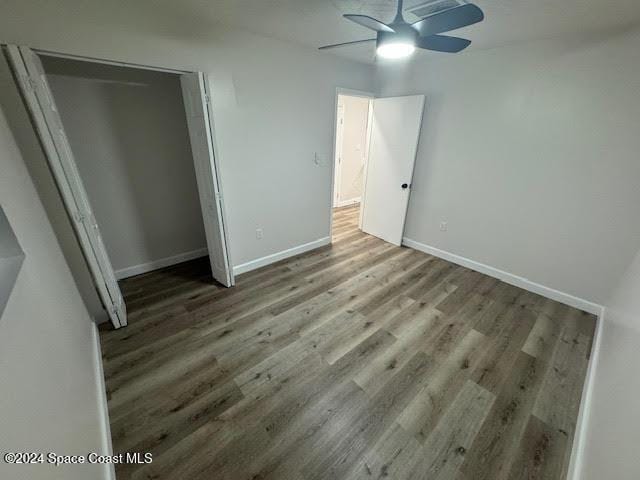 unfurnished bedroom with ceiling fan, a closet, and wood-type flooring