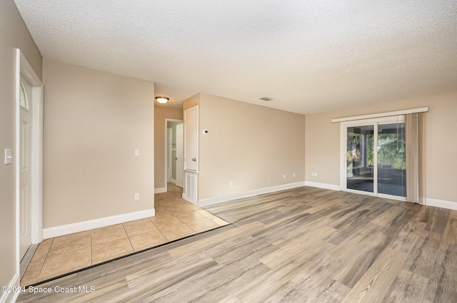 unfurnished room with light hardwood / wood-style floors and a textured ceiling