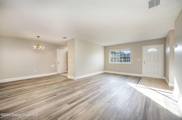 interior space featuring an inviting chandelier, a textured ceiling, and light hardwood / wood-style flooring