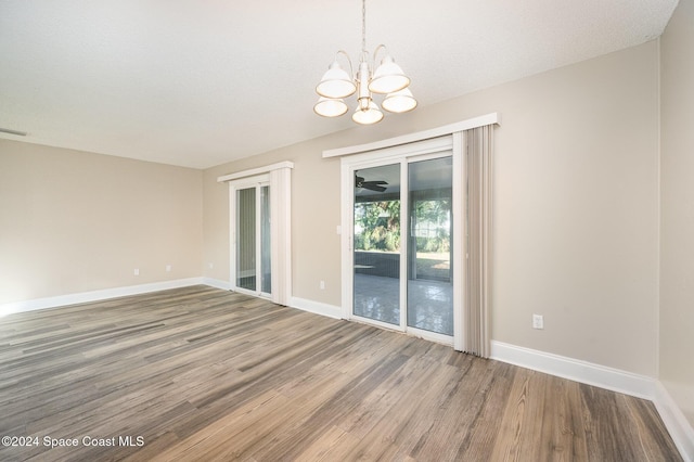 spare room featuring hardwood / wood-style floors, a textured ceiling, and an inviting chandelier