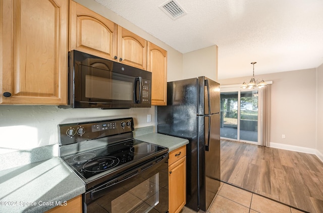 kitchen featuring a textured ceiling, black appliances, pendant lighting, light tile patterned floors, and a chandelier