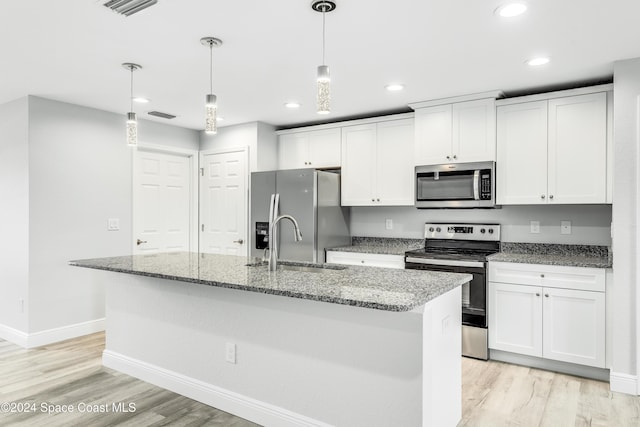 kitchen featuring white cabinets, appliances with stainless steel finishes, hanging light fixtures, and an island with sink