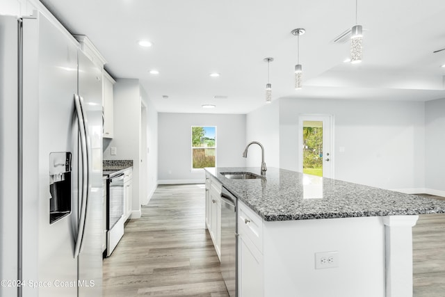 kitchen featuring white cabinets, sink, stainless steel appliances, and a center island with sink