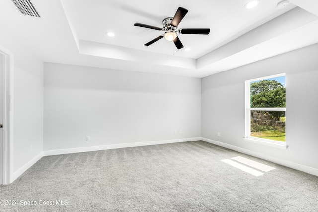 carpeted empty room featuring ceiling fan and a tray ceiling