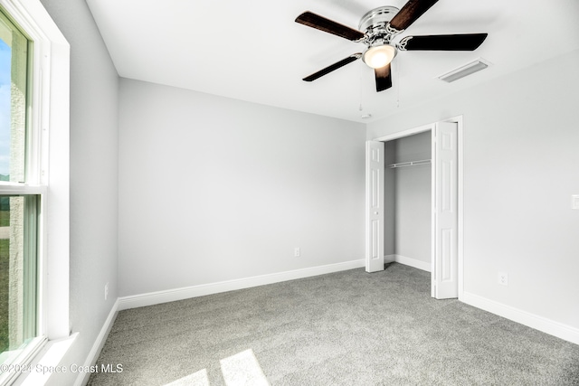 unfurnished bedroom with multiple windows, ceiling fan, a closet, and carpet floors