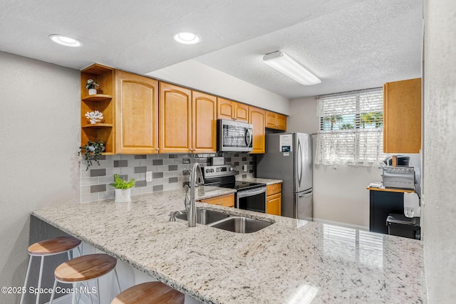 kitchen featuring sink, tasteful backsplash, kitchen peninsula, a breakfast bar, and appliances with stainless steel finishes