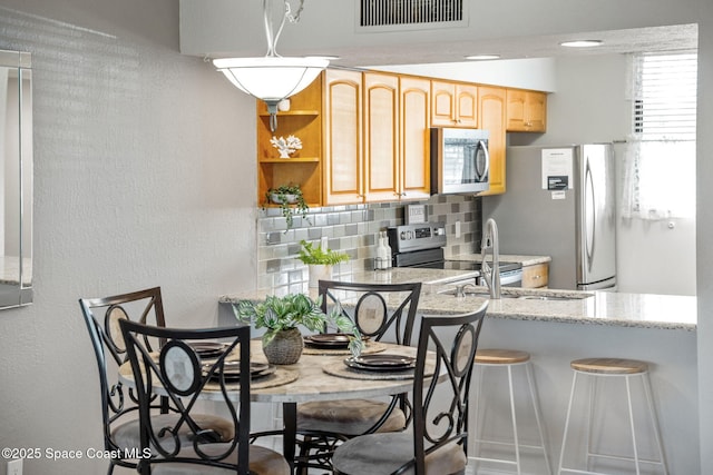 kitchen featuring a breakfast bar area, decorative backsplash, sink, and appliances with stainless steel finishes