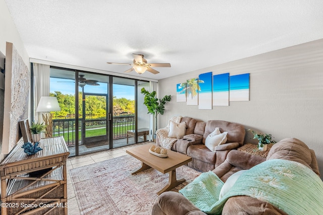 tiled living room featuring ceiling fan, a textured ceiling, and a wall of windows