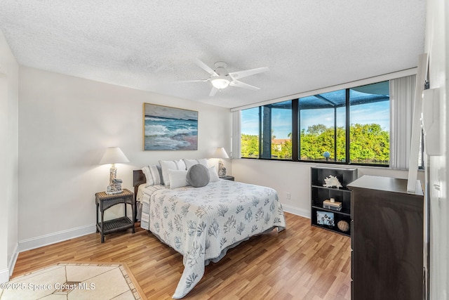 bedroom with ceiling fan, wood-type flooring, and a textured ceiling