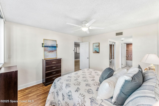 bedroom with light wood-type flooring, a textured ceiling, ensuite bathroom, and ceiling fan