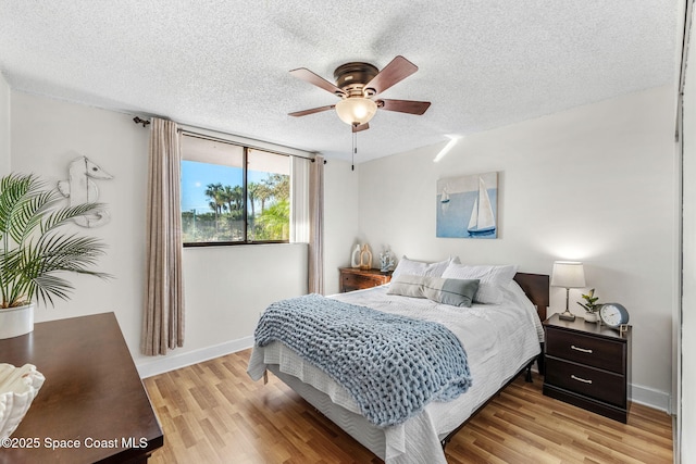 bedroom with ceiling fan, light hardwood / wood-style floors, and a textured ceiling