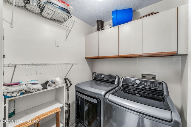 laundry area featuring cabinets, a textured ceiling, and washer and clothes dryer